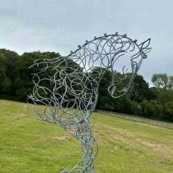 half horse sculpture in wooded area