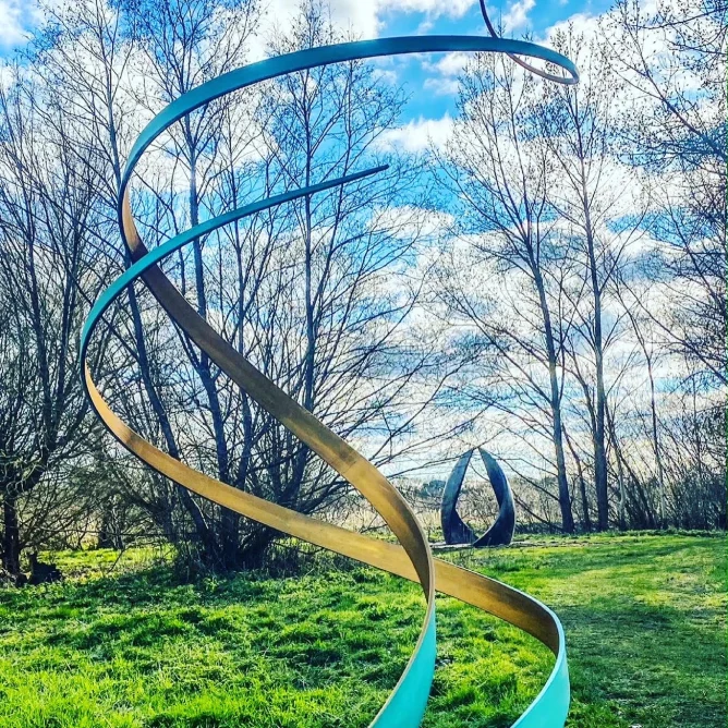 green swirl sculpture in a wooded area
