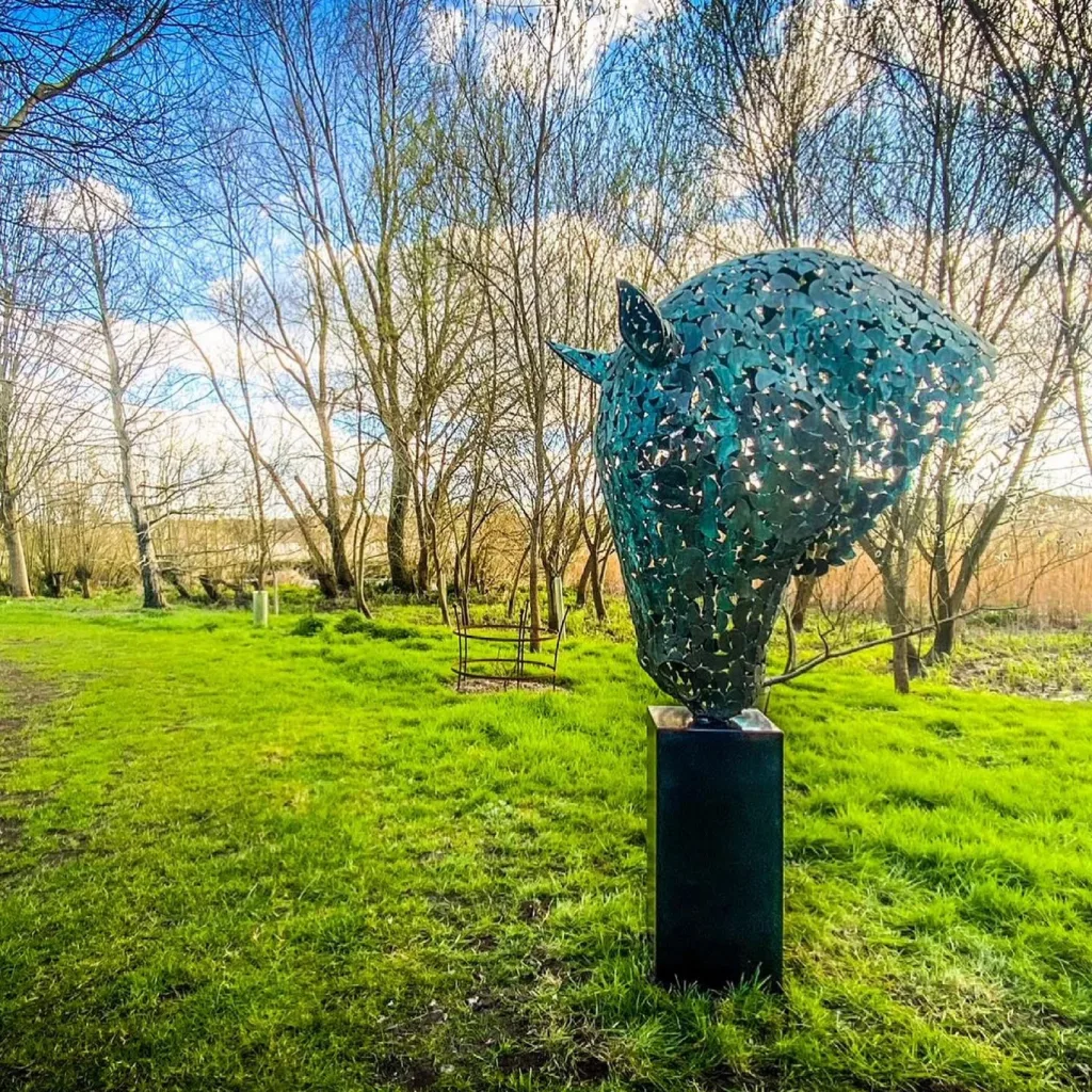 green horse head sculpture in a wooded area