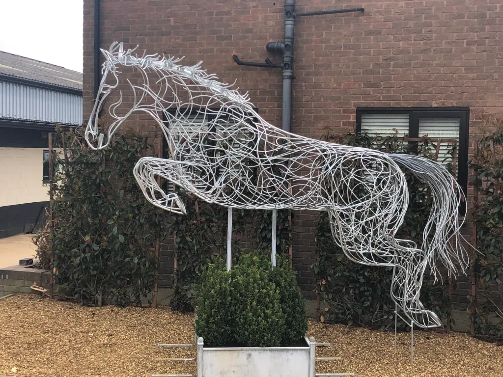 Silver Leaping Horse Sculpture In Front Of A Building