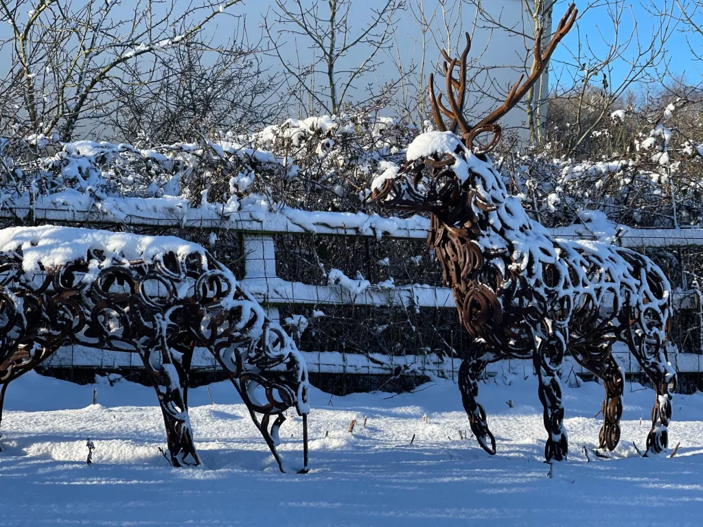 two brass horseshoe stag sculptures covered in snow