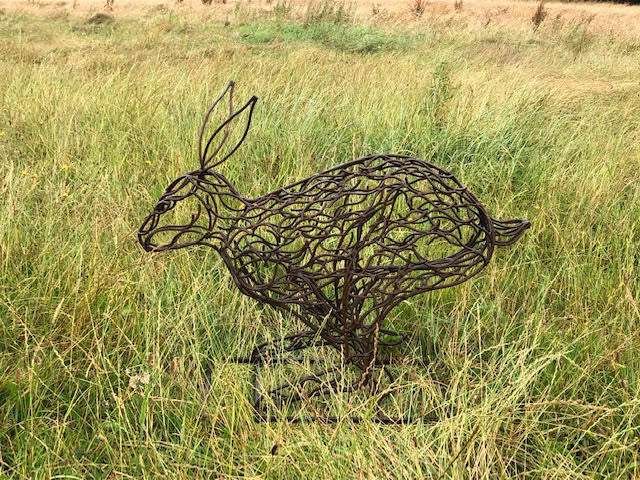 small bronze hare sculpture in tall grass