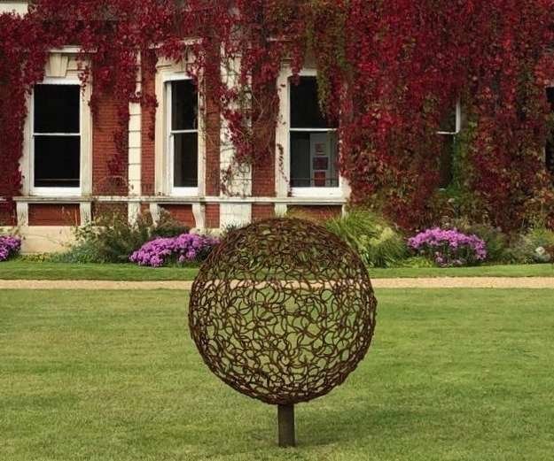 bronze horse shoe sphere sculpture in front of a house