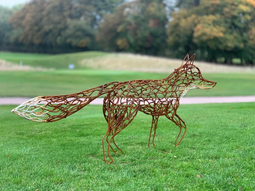 brown and white fox walking sculpture
