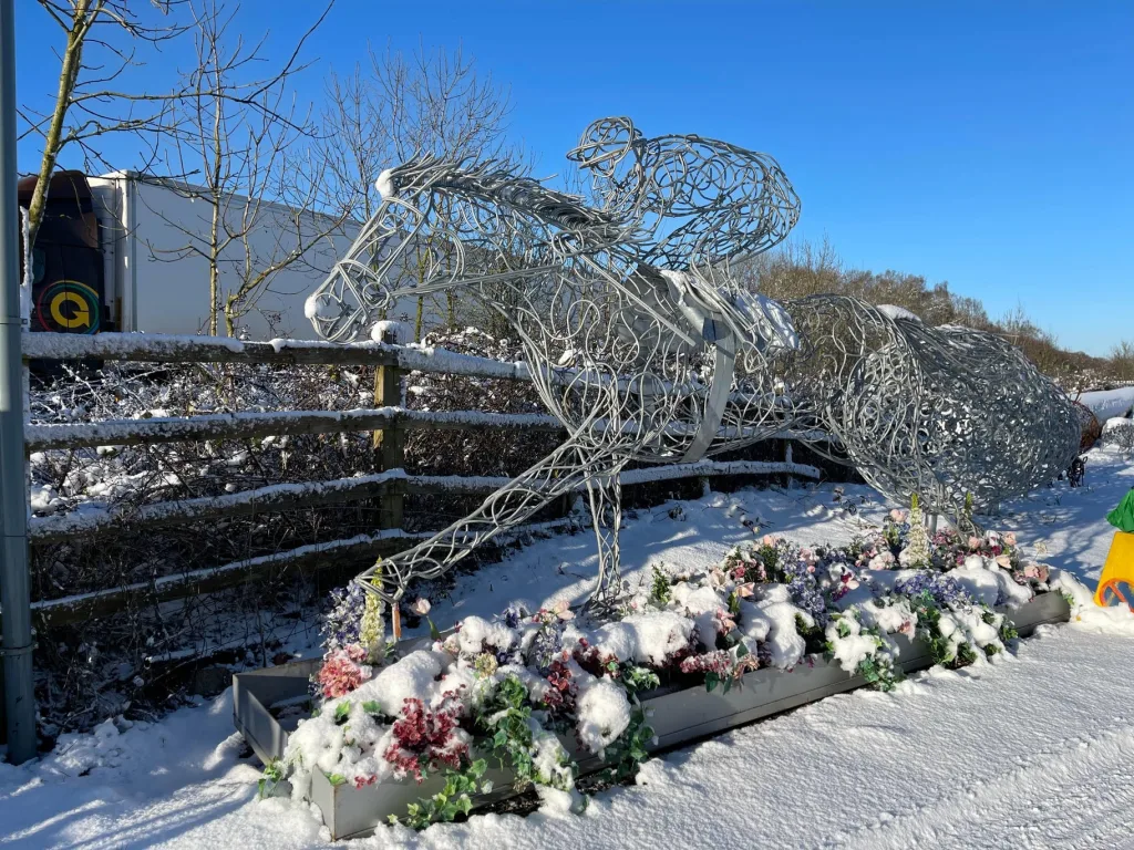 silver horse and jockey sculpture in snow