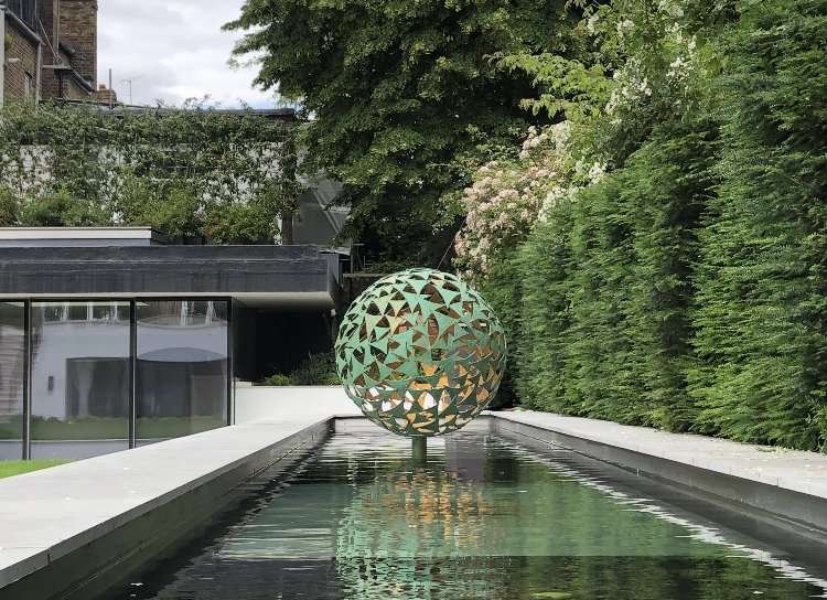 large green sphere sculpture in water feature