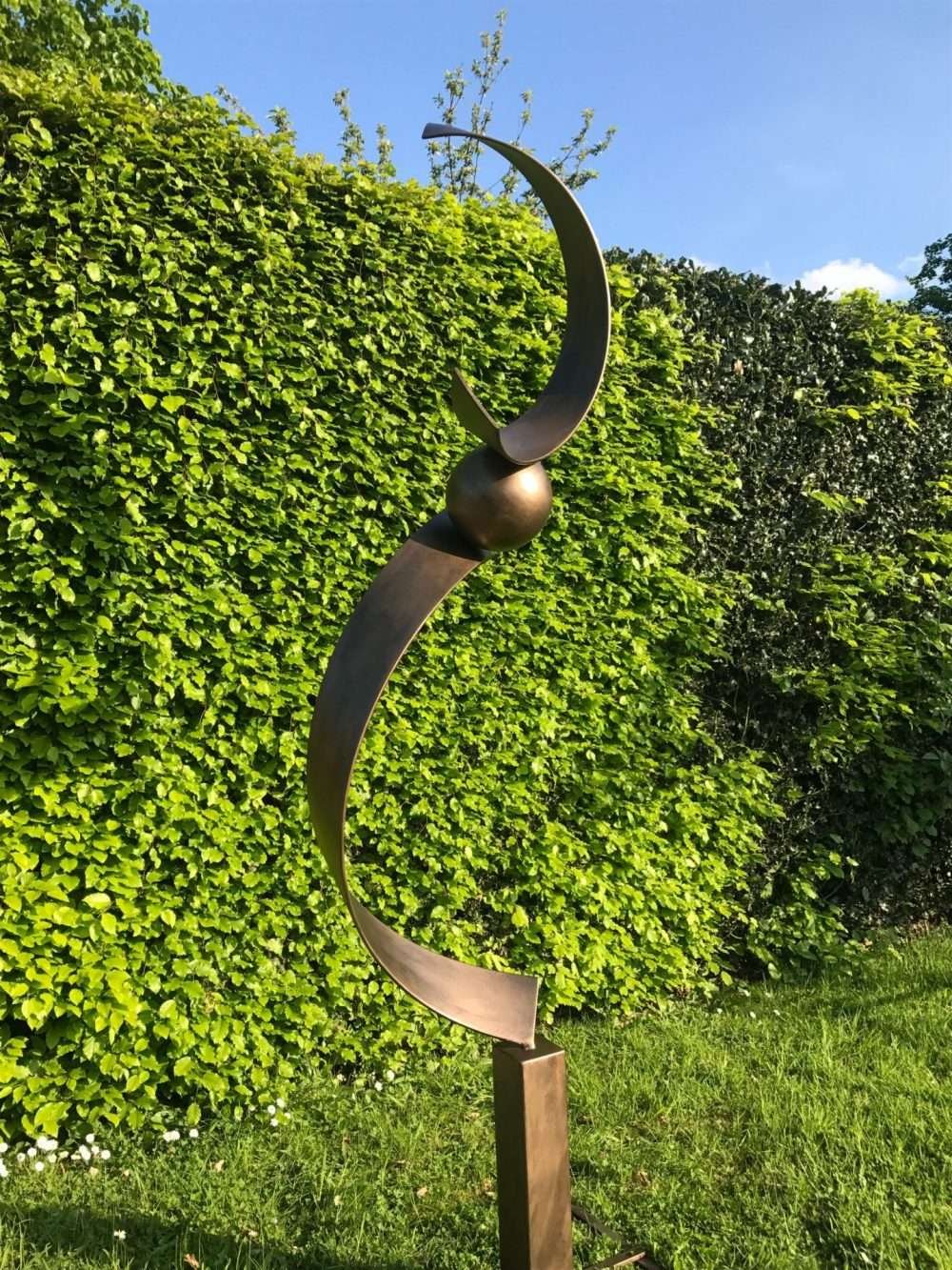 Spiral Structure Sculpture In Front Of A Hedge