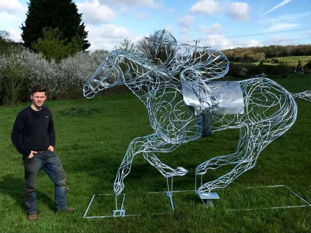 Man Standing Next To Horse and Jokey Sculpture