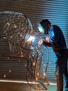 man welding a bronze sculpture