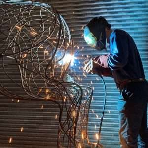 man welding a bronze sculpture