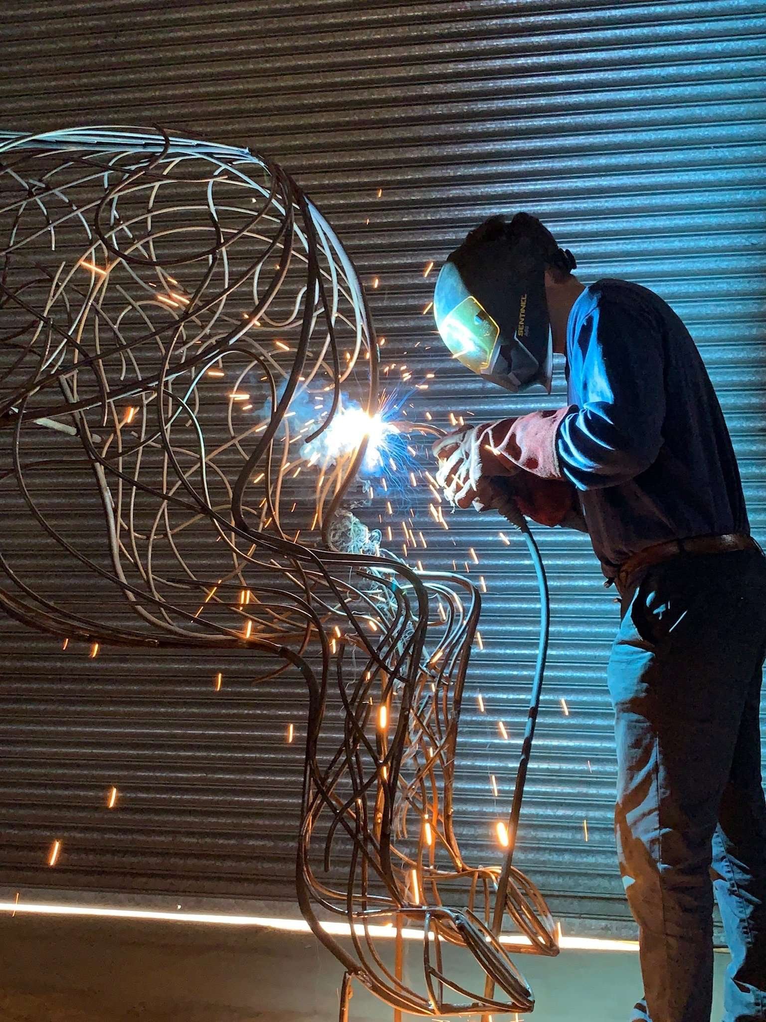 man welding a bronze sculpture